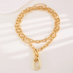 Golden double layer chain necklace with geometric U-shaped pendant on warm shaded background