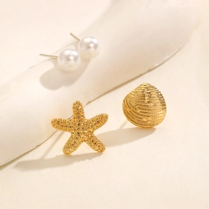 Dettaglio orecchini a stella marina dorata e perle su display beige minimalista