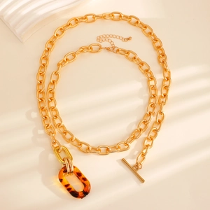 Detailed close-up of gold chunky chain necklace with amber resin ring and OT clasp