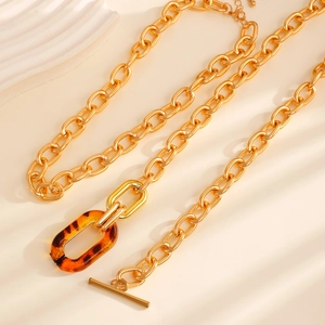 Detail of gold chunky chain necklace featuring tortoiseshell resin ring and OT toggle clasp