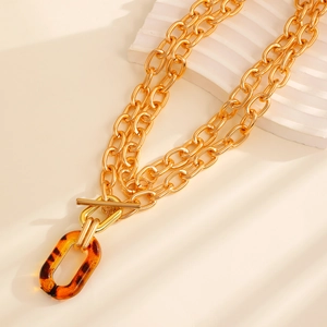 Close-up of double layer gold chain necklace with toggle clasp and leopard resin pendant
