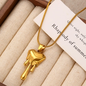 Detailed close-up of golden lava heart pendant necklace on a beige velvet jewelry tray