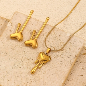 Detail of golden fluid lava heart jewelry set with necklace and drop earrings on stone