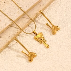 Detailed view of golden lava heart necklace and earrings on a textured stone plate