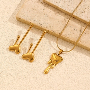 Lava-style gold heart necklace and earrings set displayed on a textured beige stone
