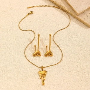 Close-up of golden lava heart pendant necklace and matching earrings on textured surface
