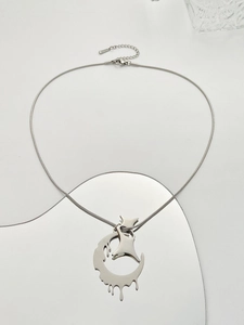 Macro detail of silver crescent and star pendant on a snake chain with mirror reflection