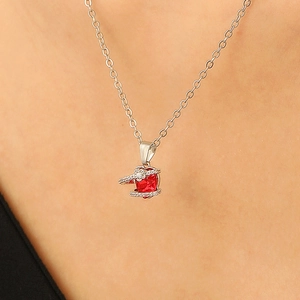 Close-up of heart-shaped necklace with red zircon center and silver-colored chain on neck