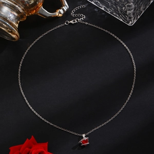 Close-up of heart-shaped red gemstone necklace with crystal accents on black texture