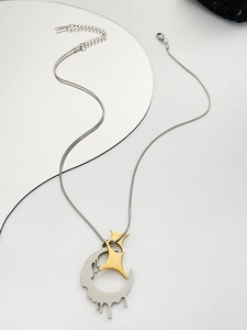 Detail of silver snake chain with gold star and melting moon pendant on minimalist stone