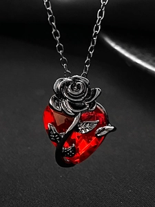 Close-up of heart-shaped red crystal pendant with a detailed black metal rose design