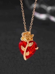 Macro shot of rose gold heart necklace with red zircon stone and intricate floral detail