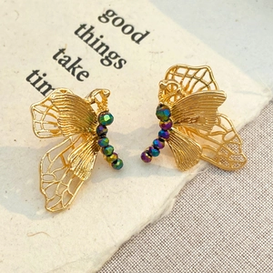 Detail of gold hollow butterfly earrings with iridescent beads on a beige card