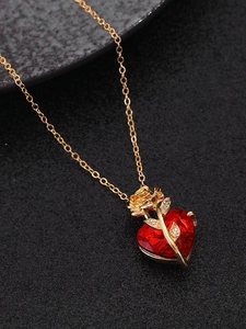 Macro view of gold rose and red heart crystal pendant on a fine necklace chain