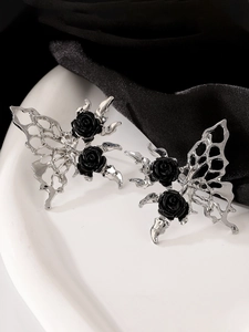Detailed close-up of butterfly stud earrings with black roses on silver hollow wings