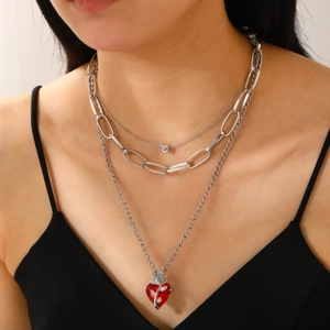 Detail of triple-layered silver chain necklace featuring red heart and rose pendant charm