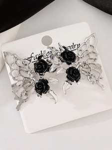 Macro detail of silver butterfly earrings with black rose accents on a jewelry card