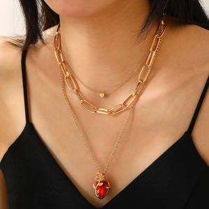 Detailed view of triple-layered golden necklace with red heart stone and rose pendant