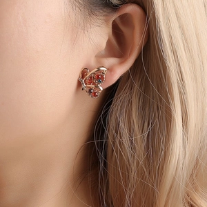 Detailed close-up of rose gold butterfly stud earring with colorful zircon crystals on ear