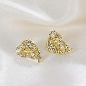 Detailed macro shot of golden butterfly stud earrings with rhinestones and pearls on silk