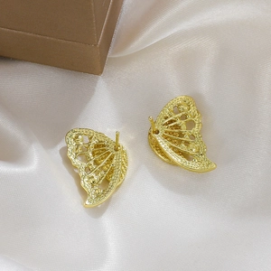 Detailed view of golden butterfly earrings with textured finish on a silk background