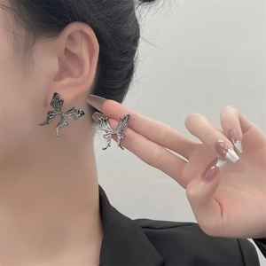 Close-up of vintage silver butterfly stud earring with Y2K gothic liquid metal design