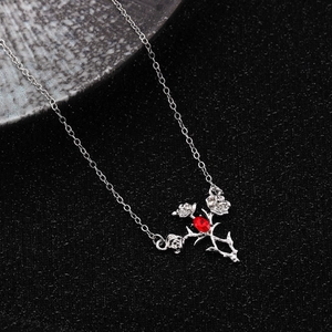 Close-up of silver rose and thorn necklace with a central oval red crystal gemstone