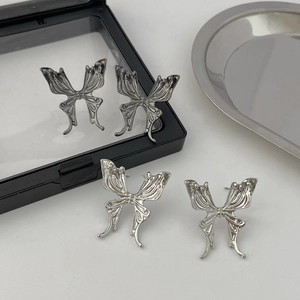 Detailed view of silver butterfly earrings with textured metal wings on minimalist tray
