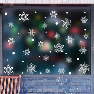 Dettaglio di vetrofanie a fiocco di neve bianche con motivi eleganti su vetro per Natale