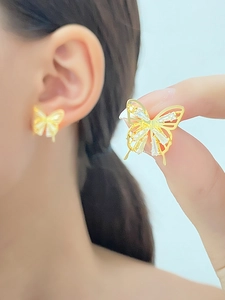Macro detail of gold butterfly stud earrings with sparkling zircon stones for women