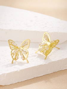 Macro shot of gold butterfly stud earrings with hollow wings and rectangle cut crystals