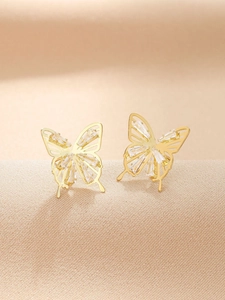 Detailed macro view of gold butterfly earrings with hollow design and inlaid cubic zirconia
