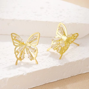 Detailed close-up of gold butterfly stud earrings with sparkling baguette diamonds
