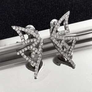 Detailed macro view of silver geometric stud earrings with pavé set crystals on a metal tray