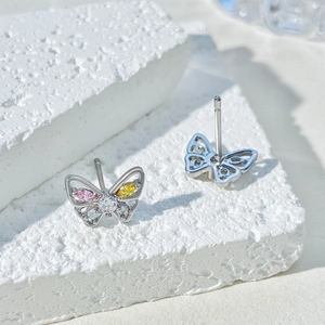 Macro view of butterfly earrings with colorful zircon stones on white stone base