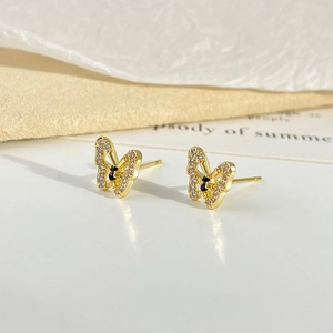 Macro shot of gold hollow butterfly earrings with sparkling clear and black rhinestones