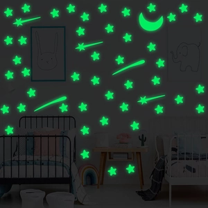 Luminous stars and moon wall stickers glowing green in a cozy children bedroom decor