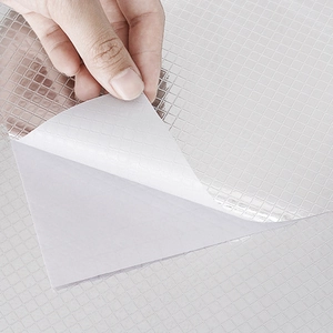 Close-up of silver grid embossed self-adhesive kitchen wallpaper showing peeling backing