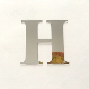 Macro detail of a silver acrylic mirror surface 3D wall sticker in the shape of letter H