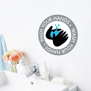 Close-up of circular 'Wash Your Hands' wall sticker in a clean modern bathroom setting