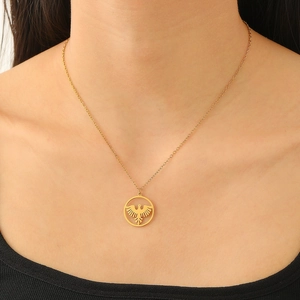 Close-up of golden eagle pendant on chain worn by a model with a dark background