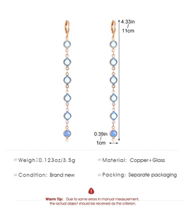 Détail de boucles d'oreilles linéaires rose doré de 11cm avec perles de verre