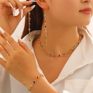 Gros plan d'un collier doré élégant orné de charmes colorés en cristal en forme de cœur