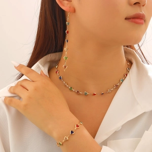 Détail d'un ensemble de bijoux coeur colorés avec collier doré, boucles d'oreilles et bracelet