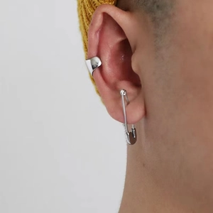 Close-up of a silver safety pin earring and wide ear cuff set on a model ear
