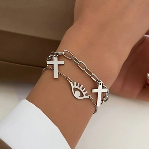 Silver chain bracelet set featuring cross pendants and evil eye charm on woman's wrist