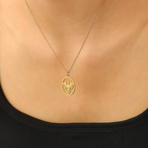 Detailed view of a gold eagle pendant on a link chain worn on the collarbone
