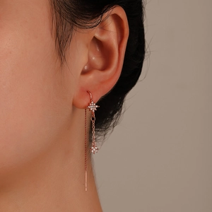 Detail of rose gold tassel earrings with zircon-studded star pendants on a model