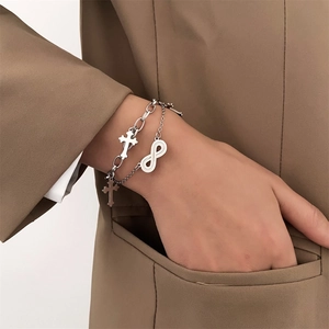 Double-layer silver metal bracelet with cross pendants and infinity symbol on wrist