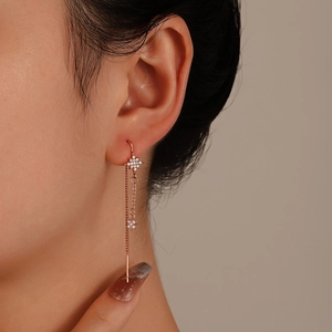 Close-up of rose gold tassel earrings with starburst elements and zircon stones